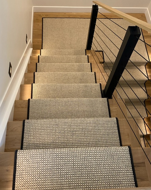 Stair runner with black serging combined with black cable railing for a modern, minimalist look in Denver.